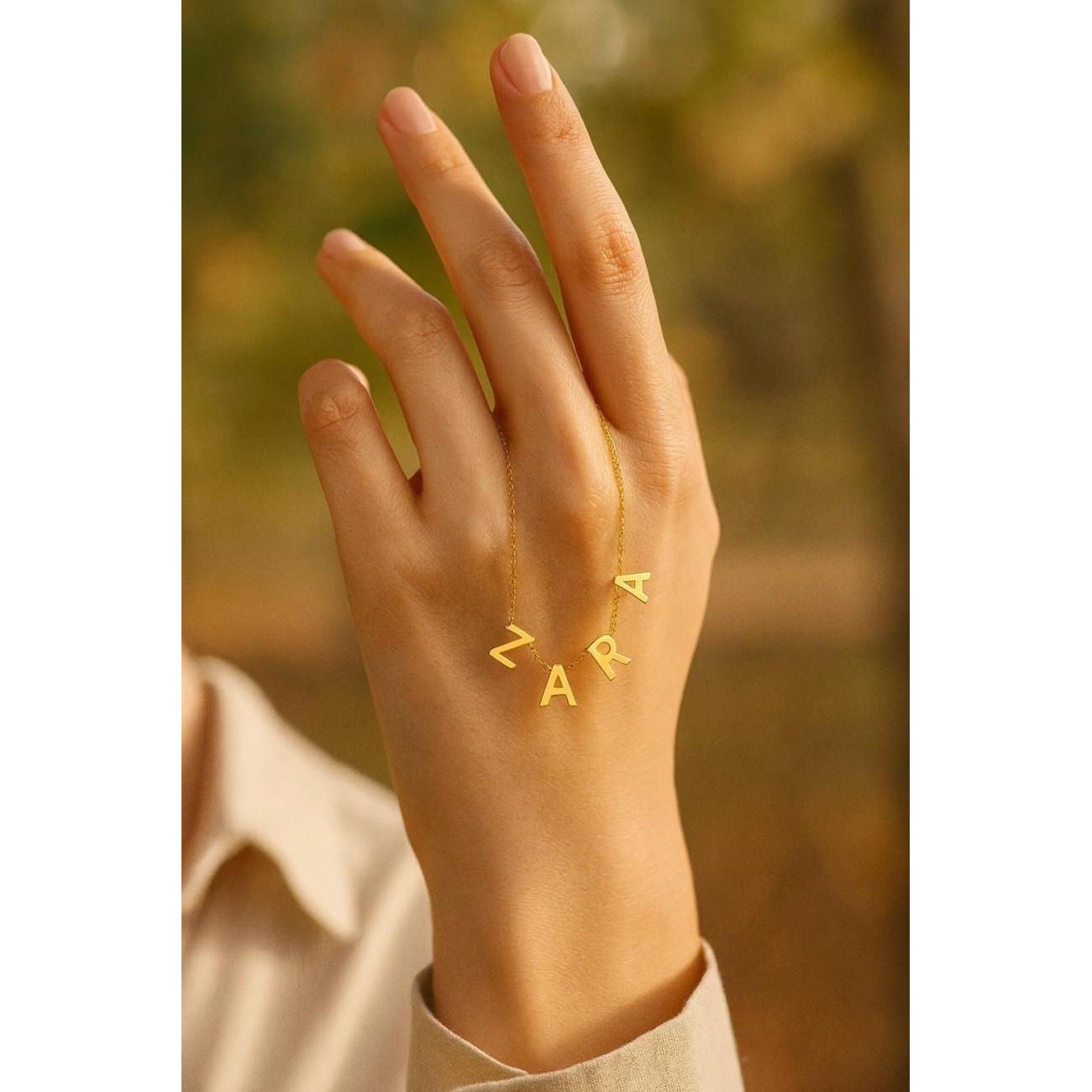 Custom gold letter necklace spelling ZARA displayed on hand